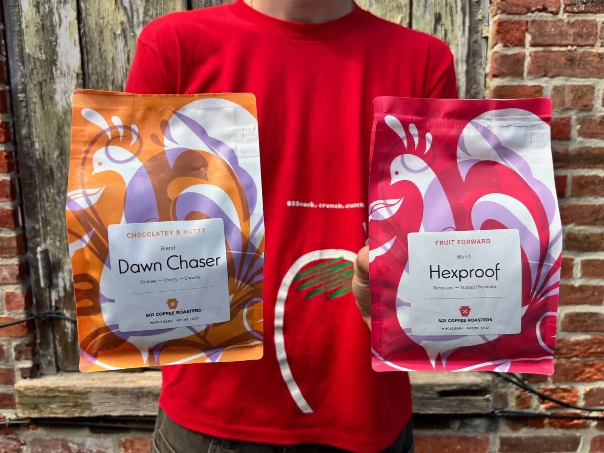 Staff holding two fresh bags outside the roastery