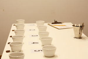 White cups arranged on a table with numbered cards and a clipboard in the background.