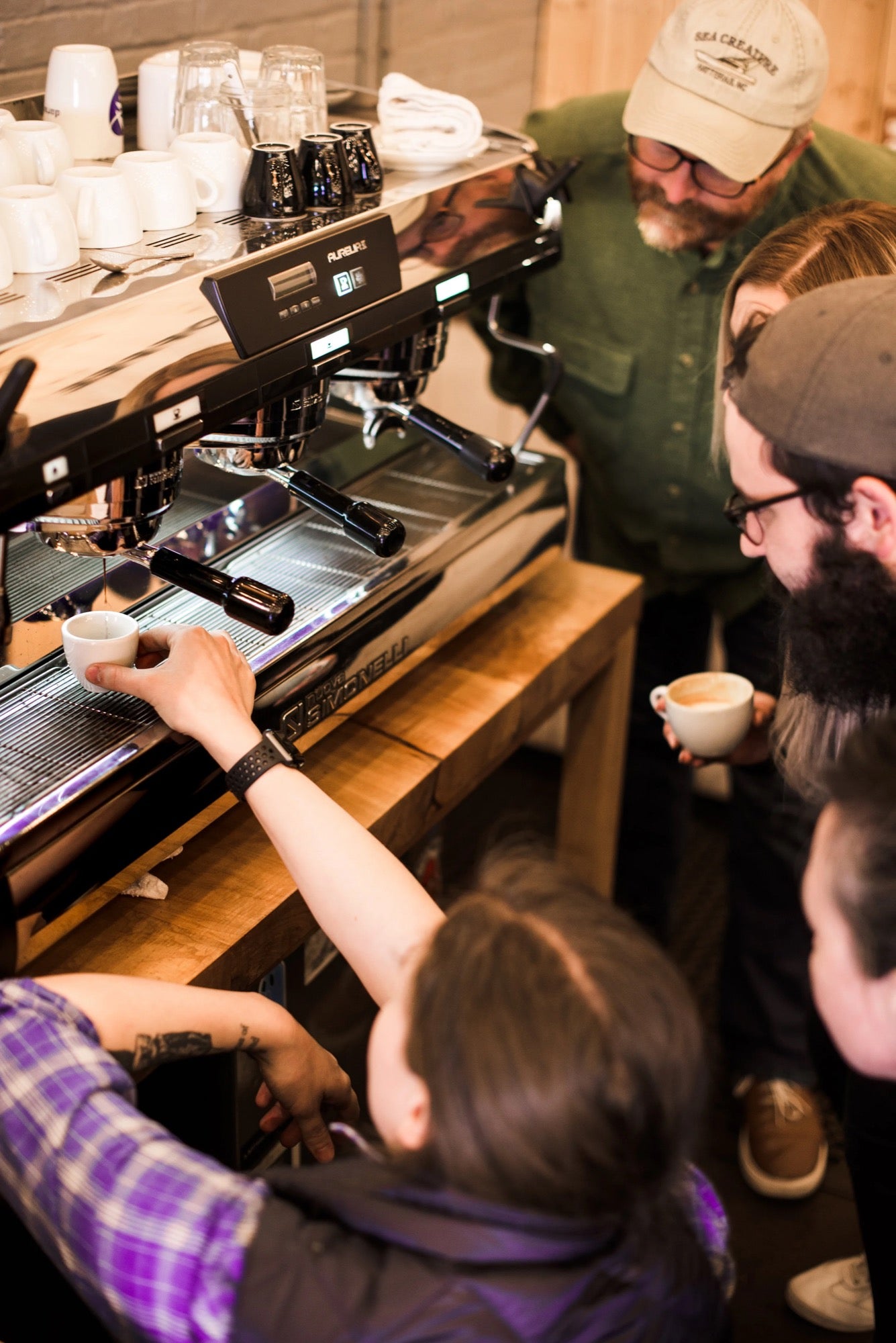 The team tasting shots together at the espresso machine